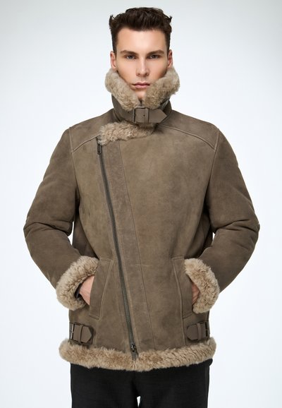 Bruine shearling jas met een hoge kraag, gestructureerde stof, ritssluiting en bontafwerking aan boorden en zoom. Eenvoudige gespsluiting als accent.