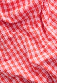 Punane ja roosa ruuduline kangas, millel on kerge, tekstureeritud põimitud muster ning vahelduvad ruudud. Pehme ja lopsaka ilmega.