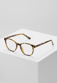 Gafas de sol carey con forma redondeada, que cuentan con un acabado brillante, un marco grueso y el nombre de la marca "QUAY" grabado en la patilla.