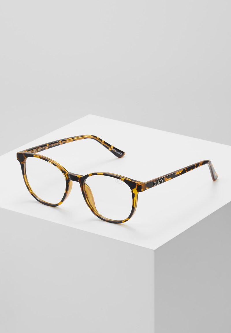 Gafas de sol carey con forma redondeada, que cuentan con un acabado brillante, un marco grueso y el nombre de la marca "QUAY" grabado en la patilla.