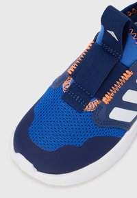 Modrá sportovní obuv s využitím síťoviny a syntetických materiálů. Má elastický pásek, oranžové šití a bílý zvýrazňující logo na straně.