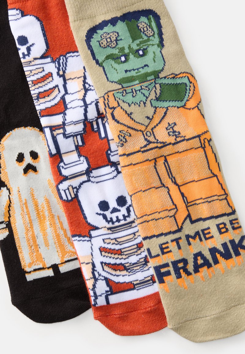 Trzy pary skarpetek z motywami halloweenowymi: duch, szkielety i Frankenstein; kolory to czarny, pomarańczowy, biały i zielony.