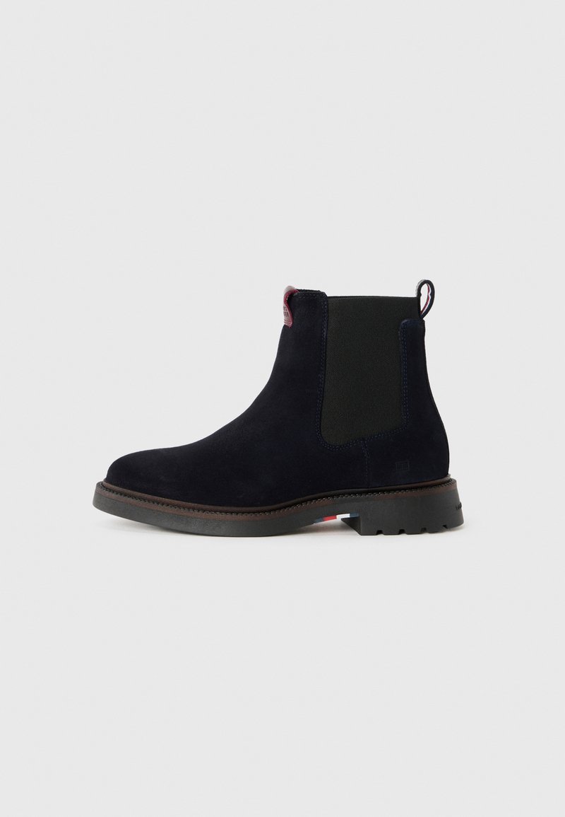 Bottines en suède marine foncé avec des panneaux latéraux élastiques, une languette et une semelle en caoutchouc texturée. Présentent des coutures minimales et un design classique.