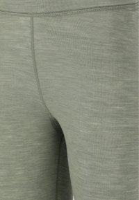 Lichtgroene leggings van een zachte, textuurstof. Voorzien van een platte tailleband en contrasterende stiksels langs de naden.
