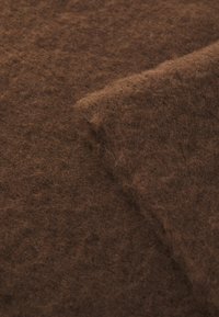 Brown felt fabric with a soft, textured surface; features a slightly folded edge showing its thickness and fluffy appearance.