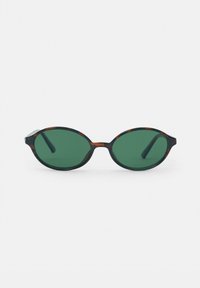 Lunettes de soleil ovales avec des verres vert foncé et une fine monture en écaille de tortue reposant sur une surface blanche.