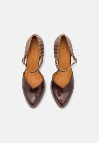 Hnědé kožené boty s lesklým povrchem, špičatou špičkou a kotníkovým páskem. Svršek má vzorovanou texturu. Interiér je podšitý světlou kůží.