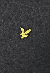 Tessuto grigio con superficie testurizzata. Logo di un'aquila dorata ricamato sul davanti, posizionato leggermente a sinistra. Nessun motivo aggiuntivo.