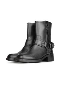 Botas de tobillo de cuero negro con cremallera lateral, puntera cuadrada y una correa decorativa con detalles metálicos. Tacón de bloque robusto. Textura suave.
