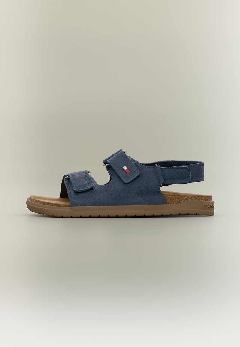 Ναυτικό μπλε πέδιλο με ανοιχτά δάχτυλα, δύο ρυθμιζόμενα λουράκια με αγκράφα και βέλκρο, μπεζ σόλα και πάτο φελλού, πλάγια όψη σε ουδέτερο φόντο.