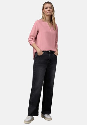 Roze blouse met lange mouwen en V-hals, gecombineerd met zwarte wijdvallende jeans en witte sneakers. Soepele textuur, ontspannen pasvorm en klassiek ontwerp.