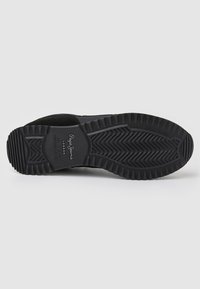 Black sneaker sole with a textured rubber bottom, featuring zigzag patterns and a logo. The design includes traction grooves for grip.