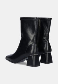 Botas de cuero negro hasta el tobillo con punta afilada, forma estructurada y un tacón grueso. Cuenta con una cremallera en el lado interior para facilitar su uso.