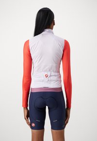 Conjunto de ciclismo que incluye un maillot de manga larga blanco y naranja con cuello alto, combinado con unos pantalones cortos de ciclismo azul marino. Presente el logo de una marca destacada.