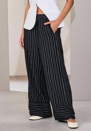 Schwarz-weiß gestreifte, weit geschnittene Hose mit elastischem Bund, seitlichen Taschen und glatter Stoffstruktur.