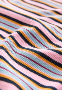 Kudottu kangas, jossa vaakasuorat raidat vaaleanpunaisena, vaaleansinisenä, keltaisena, mustana ja punaisena. Pinta on poimuttunut ja pehmeä.