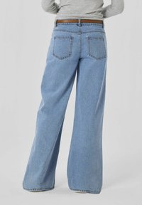 Ljust blå vida denimjeans med hög midja, två bakfickor och ett kontrasterande brunt bälte, visade från baksidan.