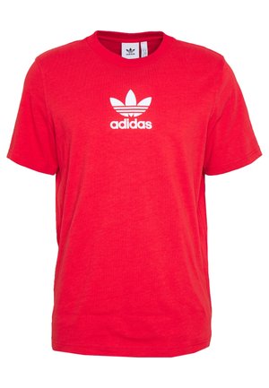 T-shirt Adidas rouge à manches courtes avec logo trèfle blanc et texte "adidas" centrés sur la poitrine, col rond, et étiquette intérieure visible.