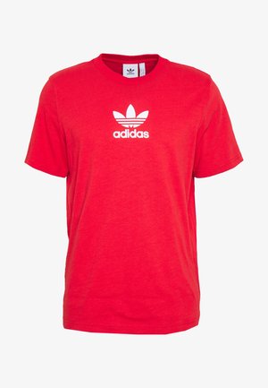 Czerwona koszulka Adidas z krótkim rękawem, z białym logo trefoil i napisem "adidas" na środku klatki piersiowej, okrągłym dekoltem i widoczną wewnętrzną metką.