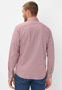 Rot-weiße Gingham-Karomuster Langarmbluse mit Button-Down-Kragen und abgerundetem Saum, hergestellt aus gewebtem Stoff.