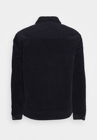 Corduroy jas in donker marineblauw. Heeft een verticale ribstructuur, een spitse kraag en manchetten met knopen. Opvallend ontworpen zonder voorzijde details.