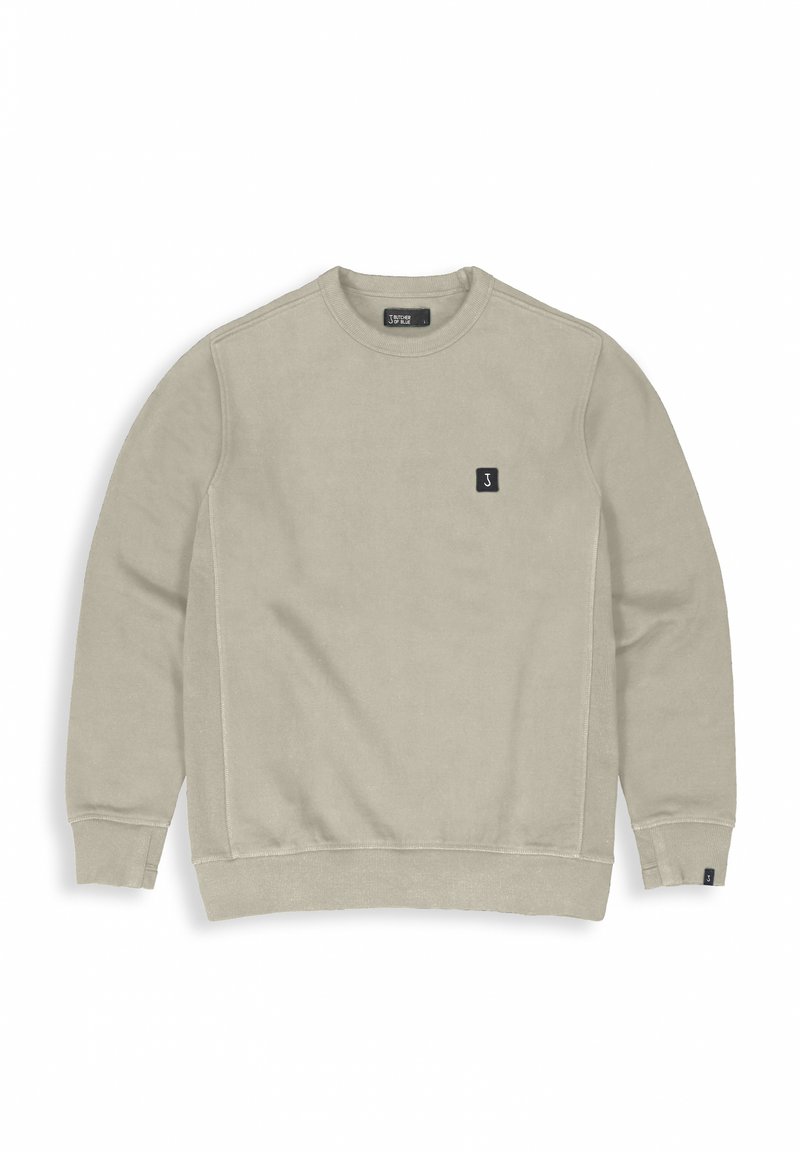 Beige sweatshirt with long sleeves, round neck, and ribbed cuffs. Features a small logo patch on the chest. Soft fabric texture.