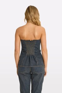 Džínový top bez ramienok so smockovaným zadným detailom, peplum spodným okrajom a svetlomodrým prešitím. Materiál má hladkú textúru a priliehavý strih.