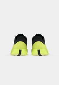 Μαύρα και νεον κίτρινα αθλητικά παπούτσια με υφή πάνω μέρος, επενδεδυμένο κολάρο και αντίθετη σόλα, σχεδιασμένα για άνεση και υποστήριξη.