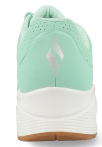 Helle mintgrüne Sportschuhe mit glatter Textur, ausgestattet mit Perforationen, einem silbernen Logo und einer weißen Zwischensohle mit Außensohle aus Gummi.