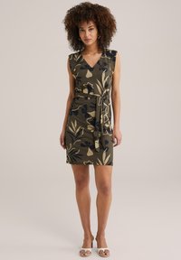 Rochie cu model floral, de culoare verde măsliniu, cu decolteu în V și talie ajustată cu un brâu. Design fără mâneci, caracterizat de motive botanice negre și crem. Material neted.