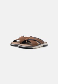 Braune Sandalen mit offenem Zehenbereich, kreuzgeführtem Riemendesign, Netzstoff, beigem Fußbett, gemusterten Akzenten und dunkler Sohle mit strukturiertem Grip.