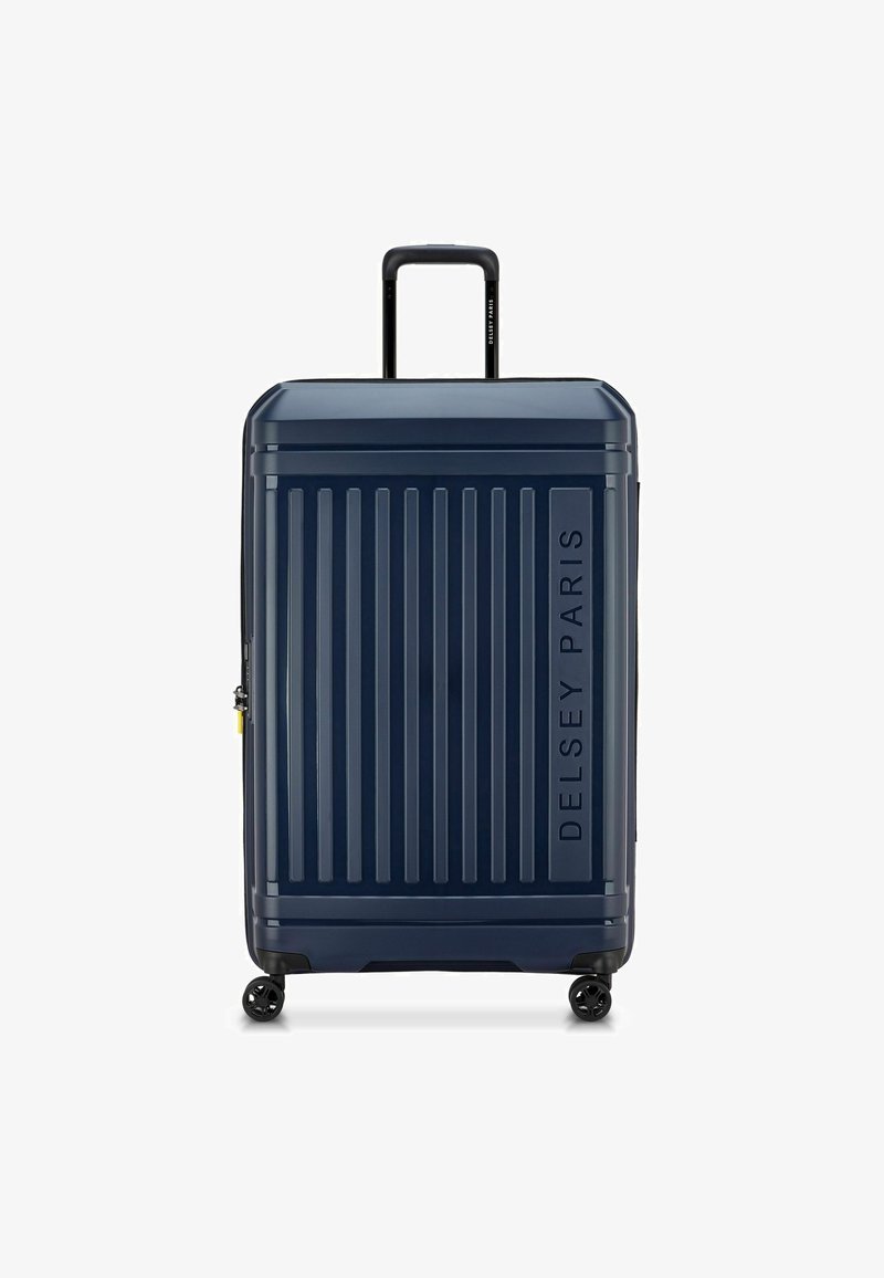 Maleta rígida de color navy con ranuras verticales, un mango telescópico único, cuatro ruedas y un logo en relieve de "Delsey Paris".