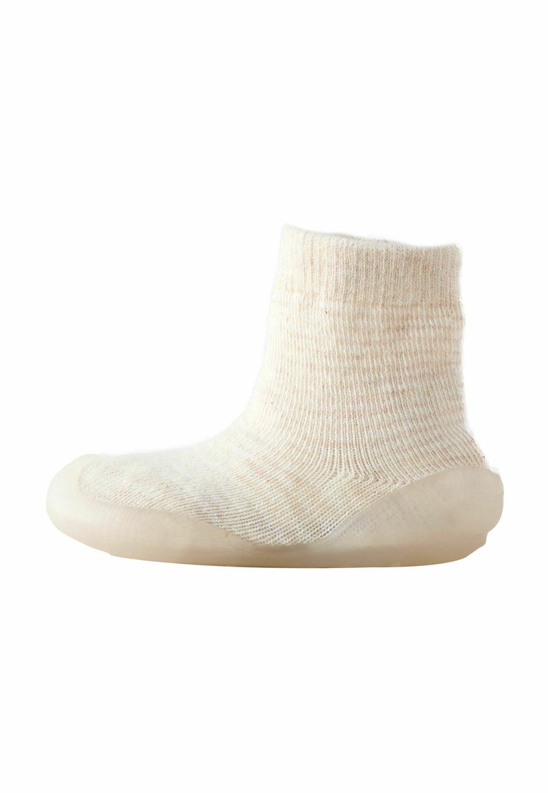 Stricksocke in Creme mit geripptem Muster, ausgestattet mit einer nahtlosen, abgerundeten Gummisohle für Langlebigkeit und Grip. Der obere Teil ist knöchellang.