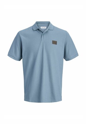 Polo bleu clair texturé à manches courtes avec col, patte de boutonnage à deux boutons et petit écusson rectangulaire sur la poitrine gauche.