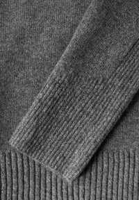 Grauer Strickpullover mit Detailansicht der glatten und gerippten Texturen, mittlerer Dicke und weichem Erscheinungsbild der Stoffoberfläche.