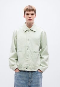 Φωτεινό πράσινο τζιν μπουφάν με άνετη εφαρμογή, κουμπιά μπροστά, δύο μπροστινές τσέπες και μυτερό γιακά. Διαθέτει μακριά μανίκια και απαλό ύφασμα.