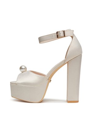 Buty na wysokim obcasie z platformą o satynowym wykończeniu w jasnobeżowym kolorze, wyposażone w pasek na palcach, regulowany pasek wokół kostki oraz ozdobę z pereł.