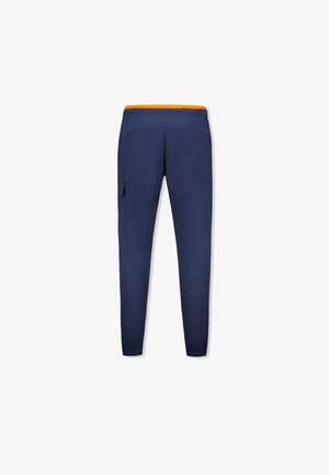 Pantalones de entrenamiento de color navy con cintura elástica, acento naranja, piernas ajustadas y bolsillo lateral tipo cargo para almacenamiento. Textura de tela suave.