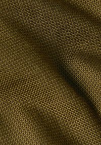 Gros plan d'un tissu tissé brun texturé avec un motif en grille, montrant des plis et des ombres qui mettent en valeur la profondeur et la texture du tissu.