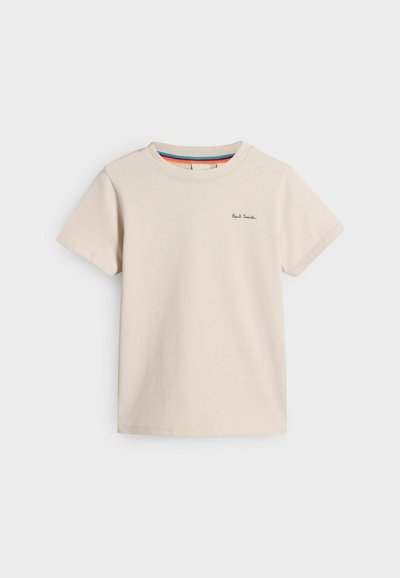 Camiseta de algodón beige con mangas cortas, que presenta un cuello redondo y un pequeño logotipo negro bordado en el pecho. Diseño simple y casual.