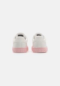 Weiße Ledersneaker mit einer rosa Gummisohle. Sie verfügen über ein geprägtes Branding an der Ferse und sind in einer abgerundeten Form mit dezenten strukturierten Akzenten gestaltet.