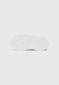 Semelle de chaussure en caoutchouc blanc avec une texture ondulée et des accents circulaires, présentant un motif de semelle pour une meilleure adhérence et un design à bord plat.