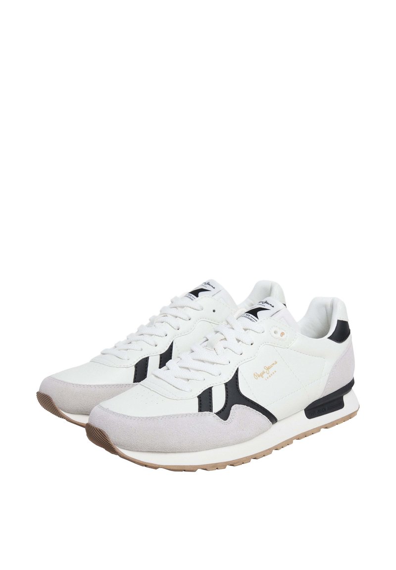 Zapatillas blancas con acentos en negro y superposiciones de ante gris. Las características incluyen cierre de cordones, cuello acolchado y suela de goma texturizada.
