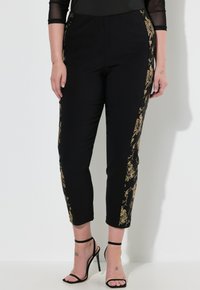 Zwarte broek met gouden bloemenborduurwerk aan de zijkanten, met een relaxte pasvorm en cropped lengte. Soepele textuur met een elastische tailleband.
