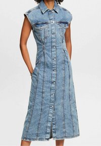 Jeansklänning med korta ärmar, framknappar, två bröstfickor och vertikala sömmar; längd till mitten av vadderna i ljusblå tvätt.