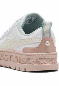 Bijele kožne tenisice s ružičastim i mint akcentima, teksturiranom potplatom, podignutim petama i prugastim petnim označivačem. PUMA logo sa strane i na jeziku.