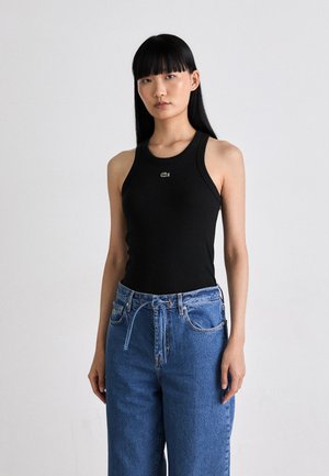 Black cotton tank top with a round neckline and thin straps, paired with loose blue denim jeans featuring a drawstring waist.