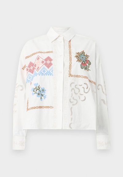 Λευκό πουκάμισο με μακριά μανίκια και κουμπιά, με καφέ περιγράμματα και κεντήματα σταυροβελονιάς με λουλουδένια σχέδια σε μπλε, κόκκινο και πράσινο στο μπροστινό μέρος και στα μανίκια.
