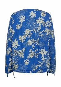 Blå jakke med blomsterprint, der har hvide blomster, lange ærmer, elastisk bund med snore og en quiltet tekstur.