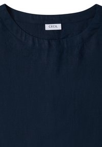 T-shirt bleu marine à col rond avec des coutures visibles et une étiquette blanche indiquant « CECIL » à l’intérieur de l’encolure.